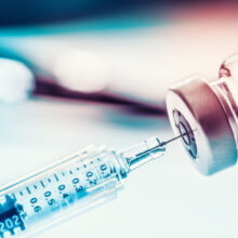 A medical syringe inserted into a vial of vaccine