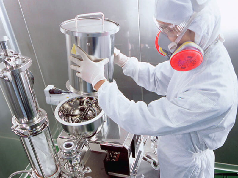 A worker inside a pharmaceutical machninery cleanroom, wearing a white coverall